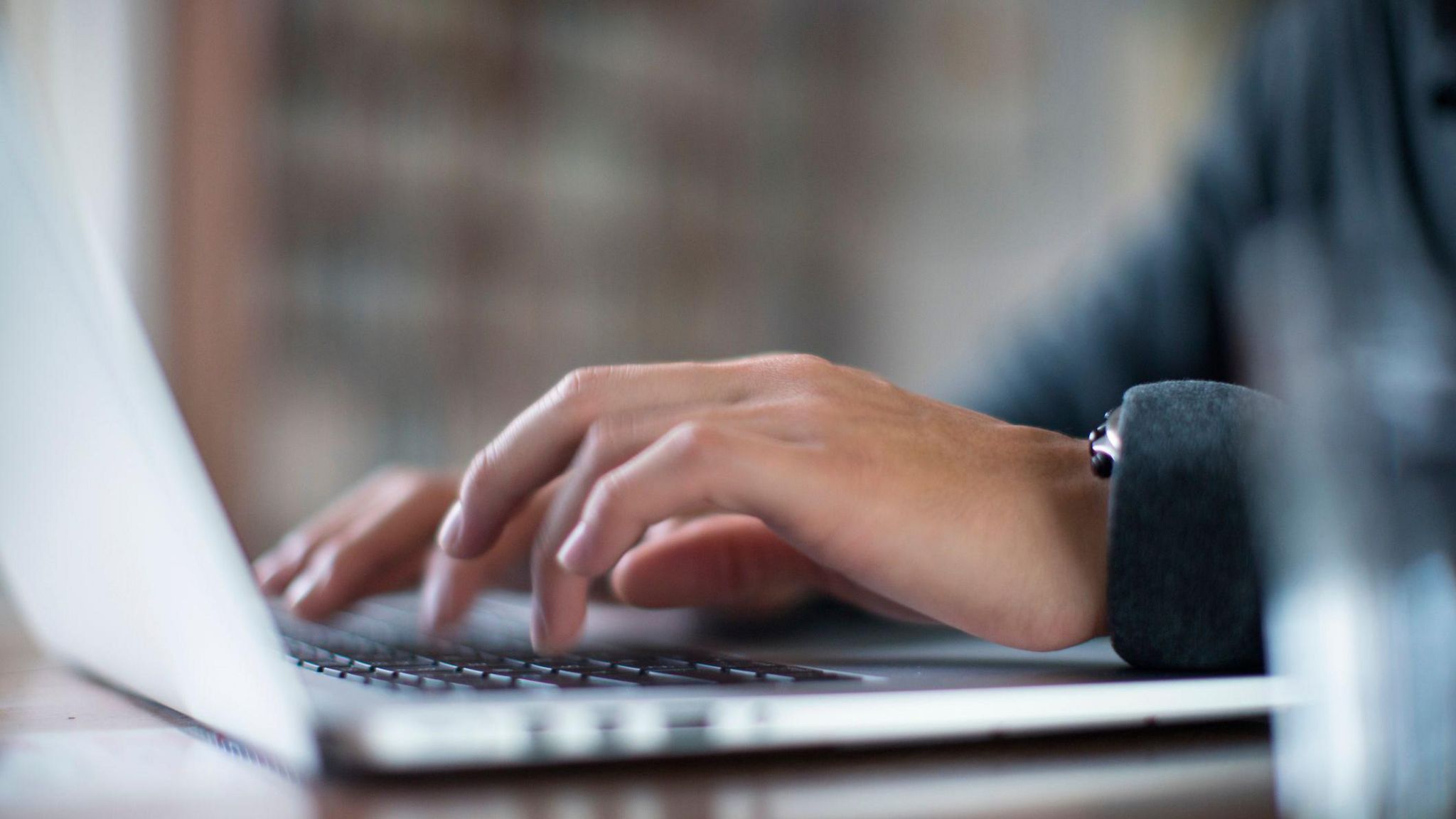 Hands type on a laptop keyboard