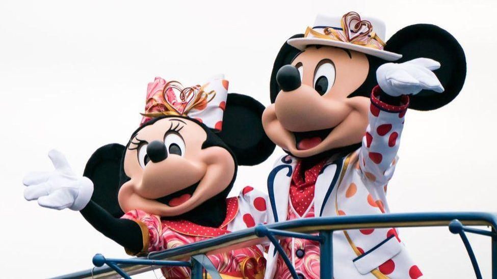 Mickey and Minnie Mouse life-sized characters waving.