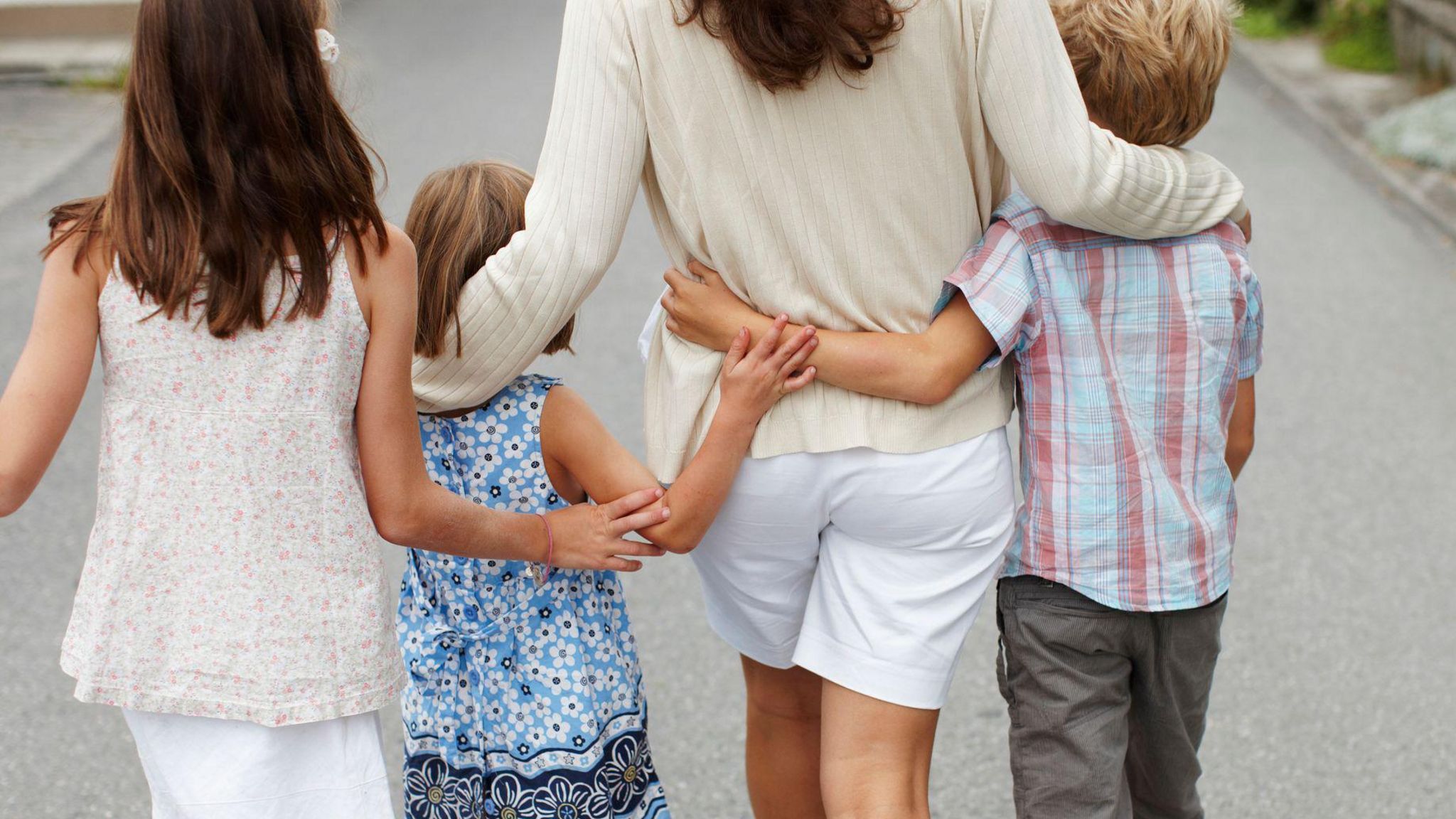 Family of woman with three children walking along the road