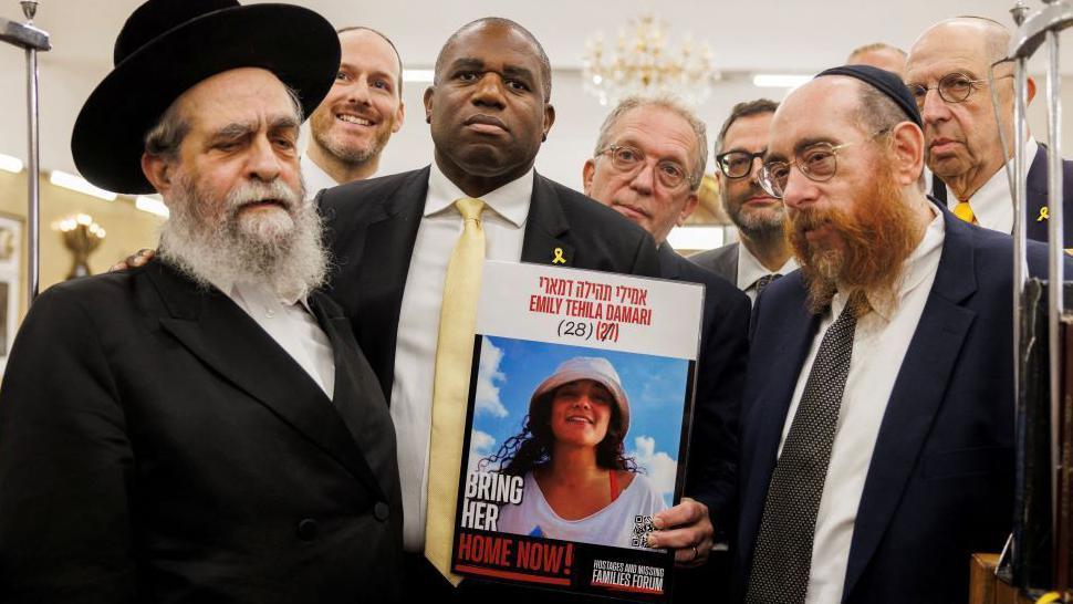 David Lammy pictured holding an image of Emily Damari 