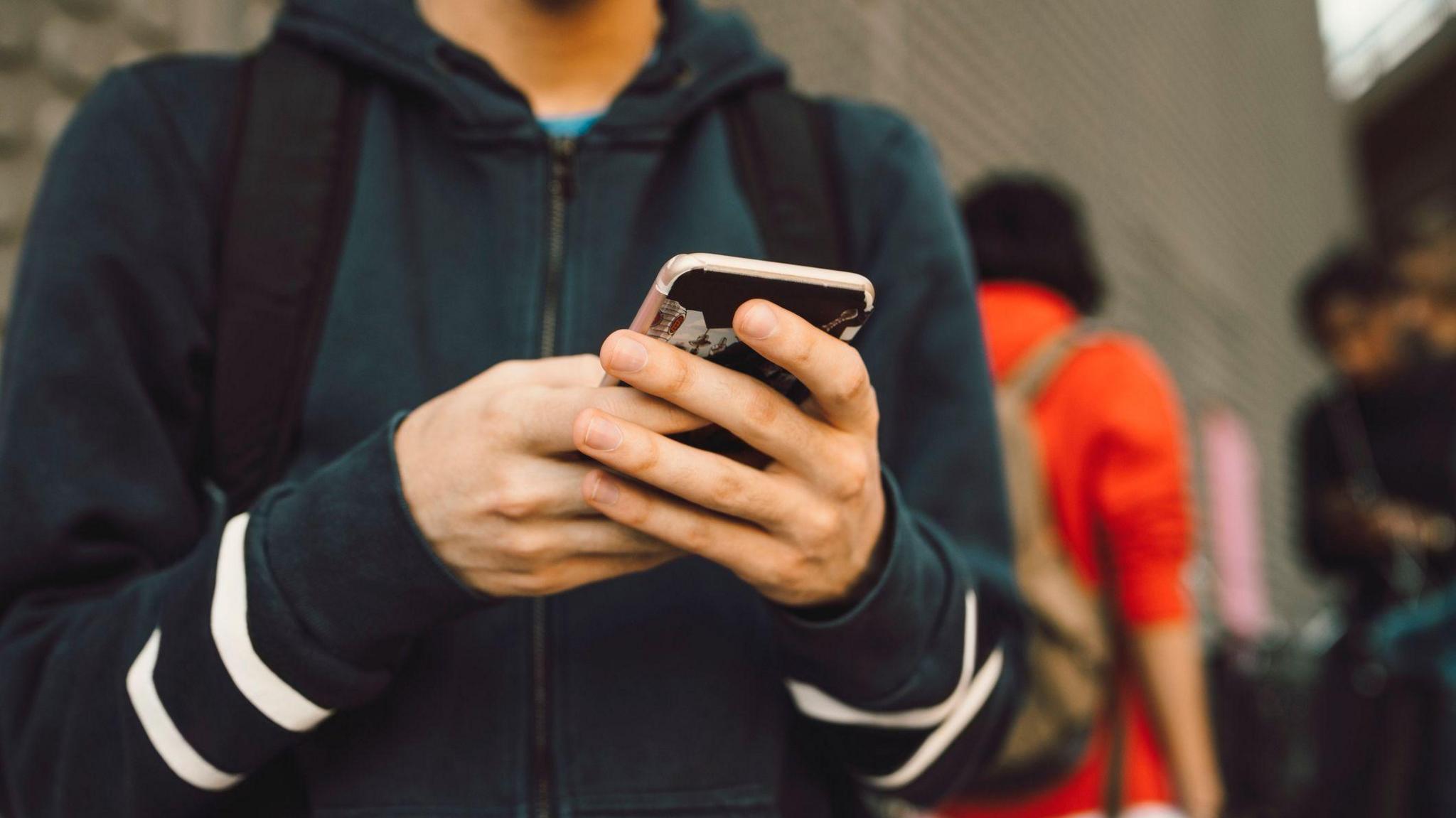 A boy holding a mobile phone.