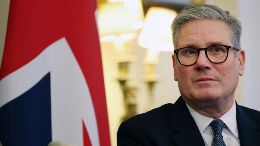 Keir Starmer sitting in front of a Union Flag.