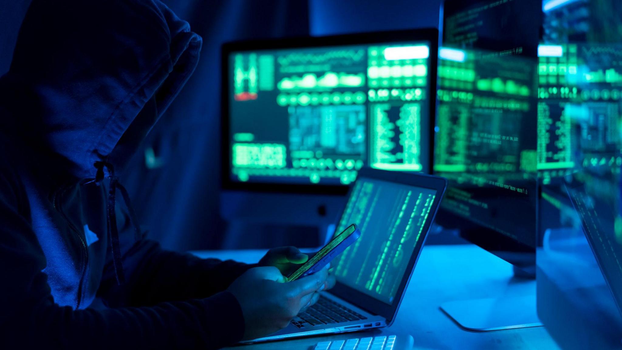 Stock photo of hacker or IT worker using computers.