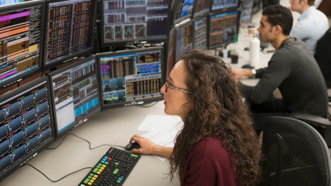 Woman looks at financial data on a number of computer screens