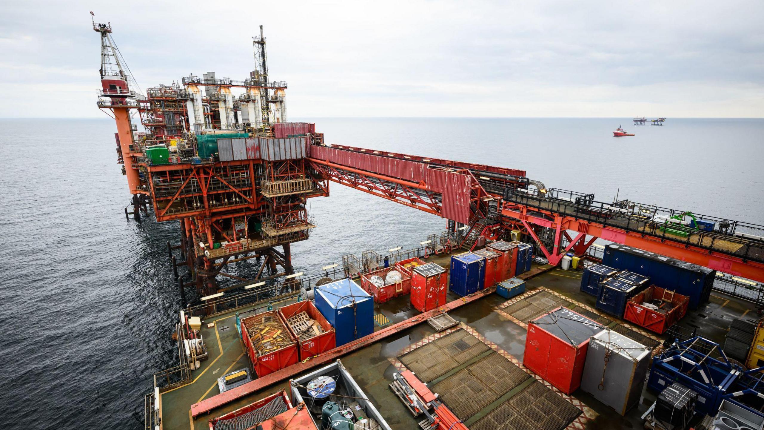 A drilling platform for oil in the North Sea The view is diagonal. A boat can be seen in the distance behind it.