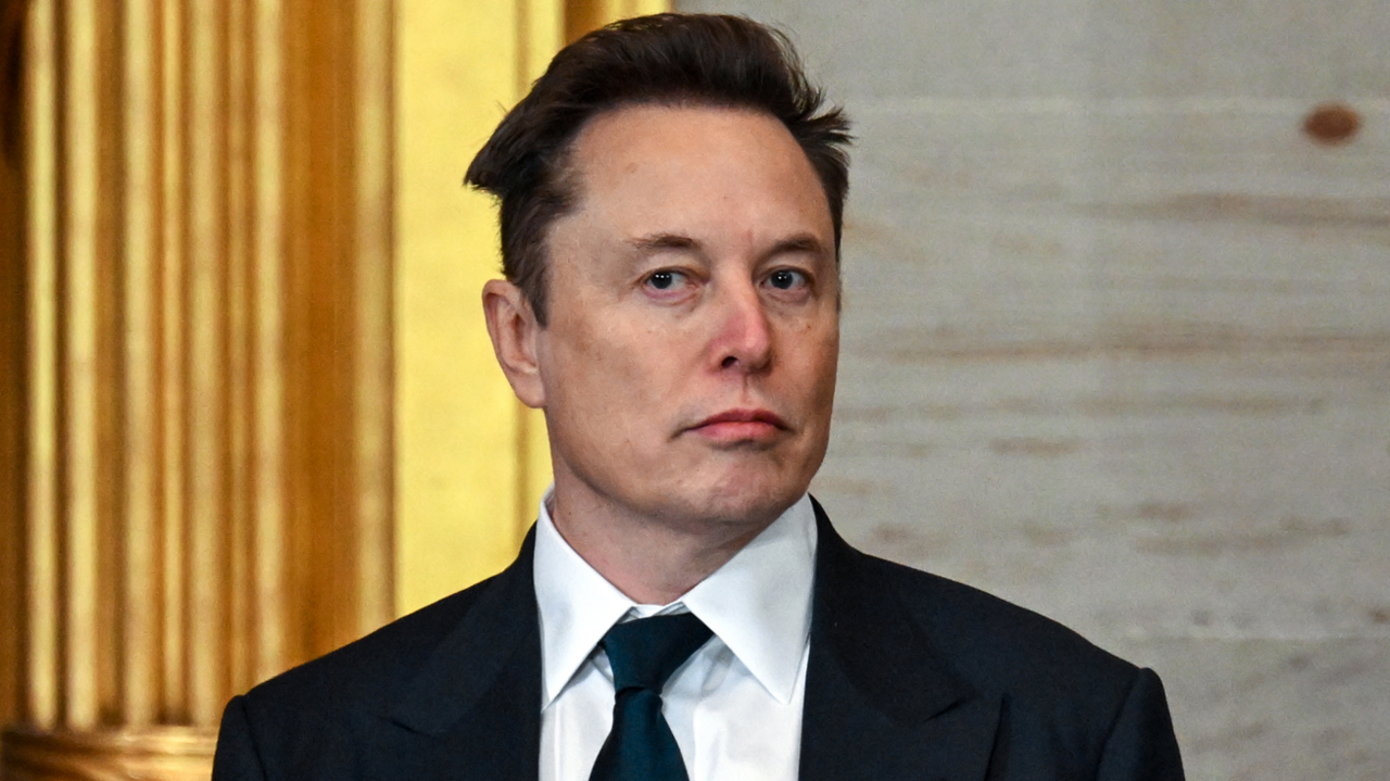 Elon Musk wearing a sharp black suit and tie