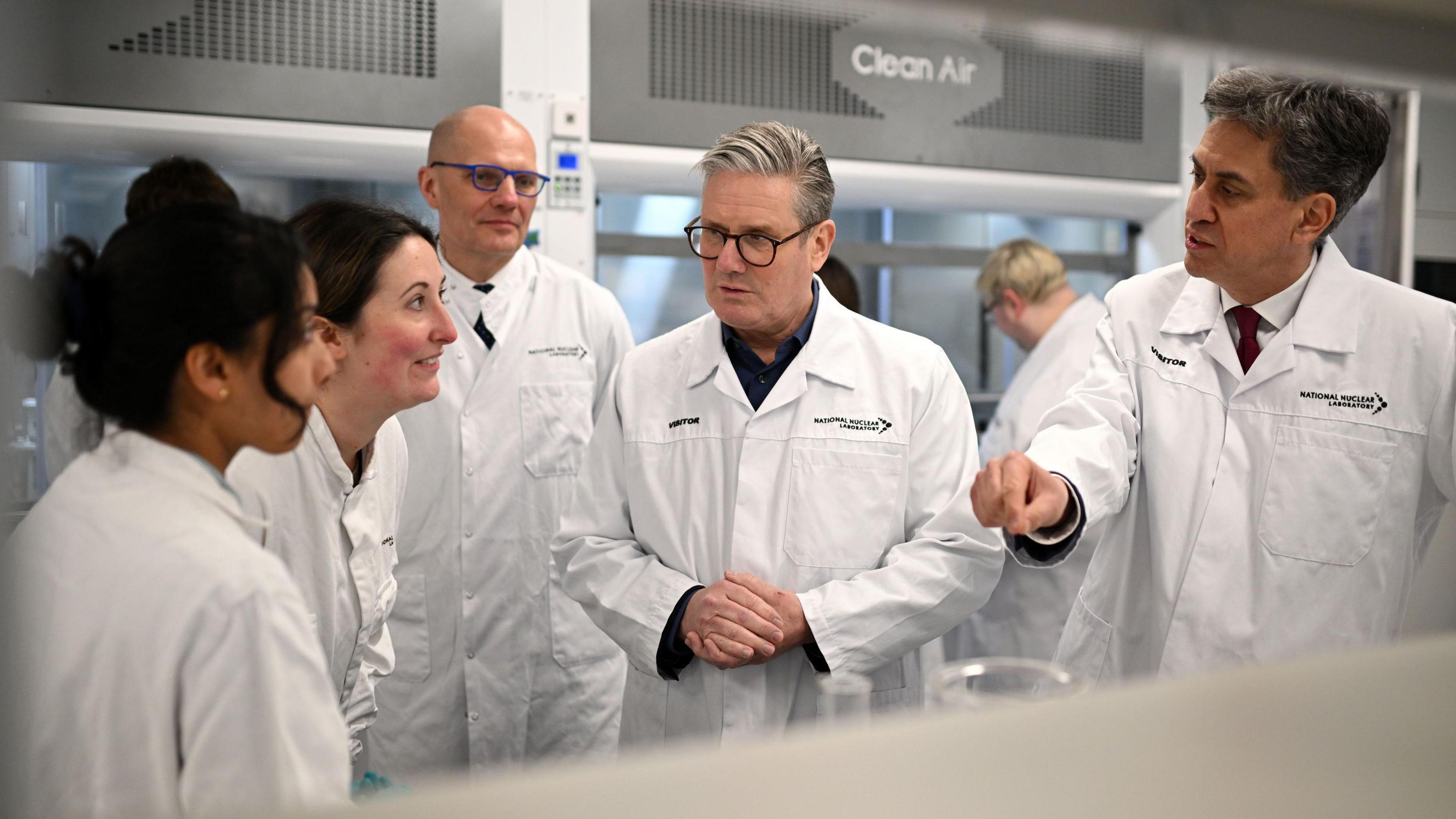 Keir Starmer and Ed Miliband wearing white coats talking to staff at the National Nuclear Laboratory facility 