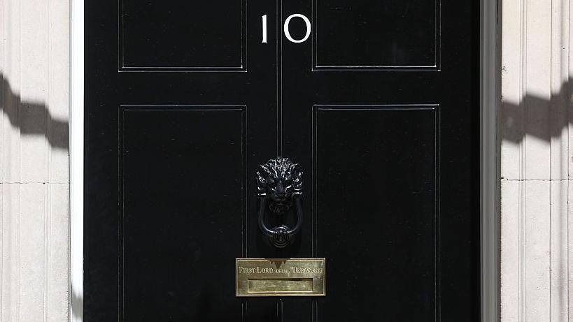The black door of 10 Downing Street, with its brass letter box labelled 'First Lord of the Treasury'