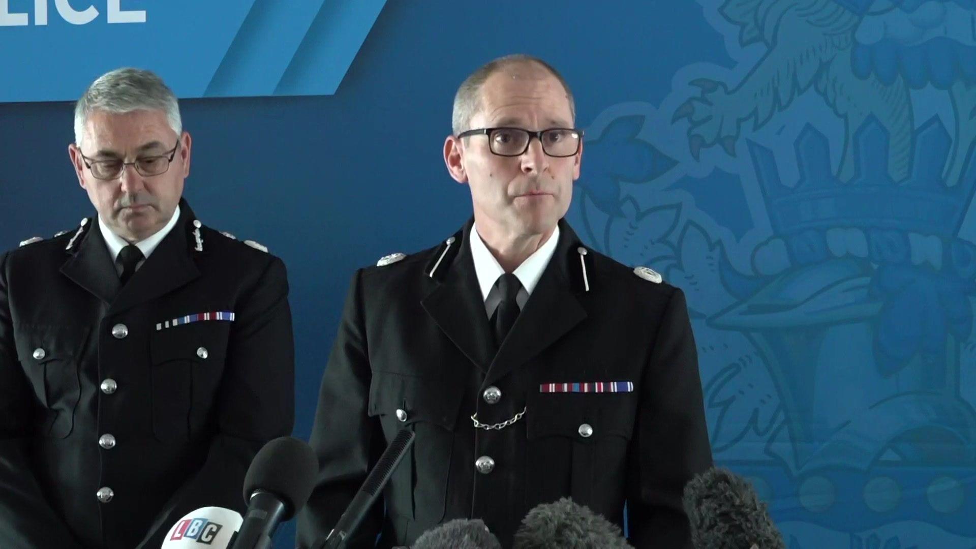 Assistant Chief Constable Matt Longman speaks to reporters at a press conference, with microphones in front of him  