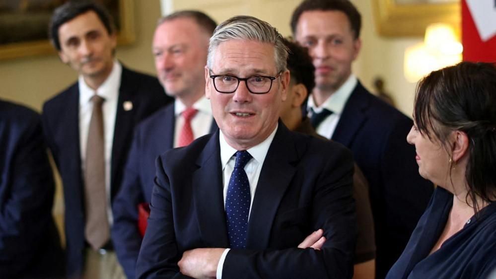 Sir Keir Starmer stands with arms folded