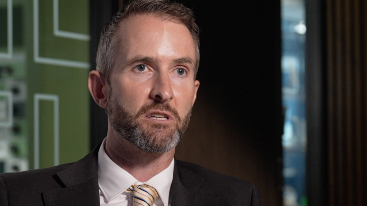 Portrait of Paul Foster seen wearing a suit and tie indoors.