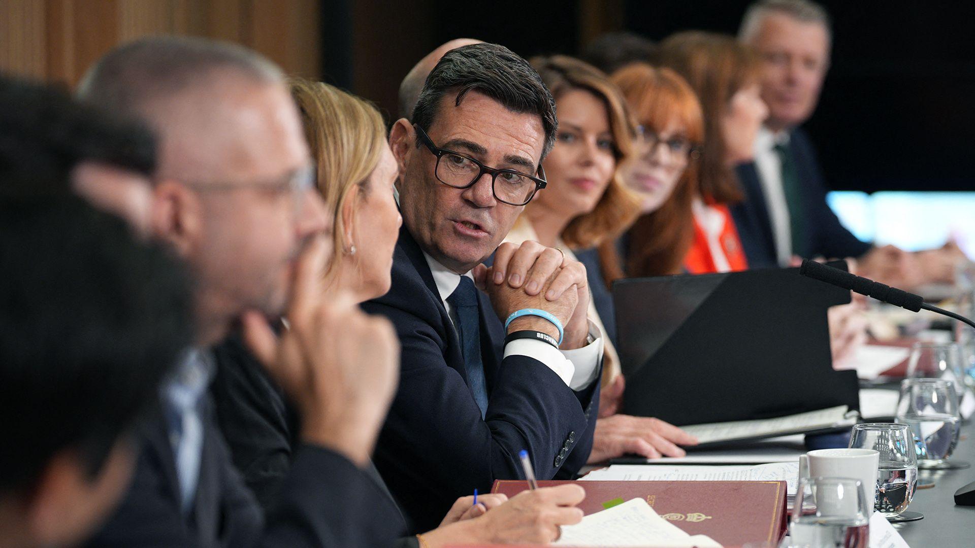 Andy Burnham clasps his hands as he looks towards camera while speaking to others sitting on a long table at a meeting of the National Economic Council in Manchester on 24 July.