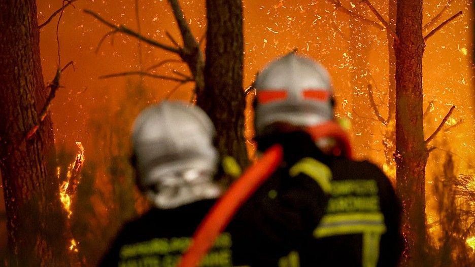Two firefighters direct a hose at a burning forest around 30km from Bordeaux, on July 26, 2026. 