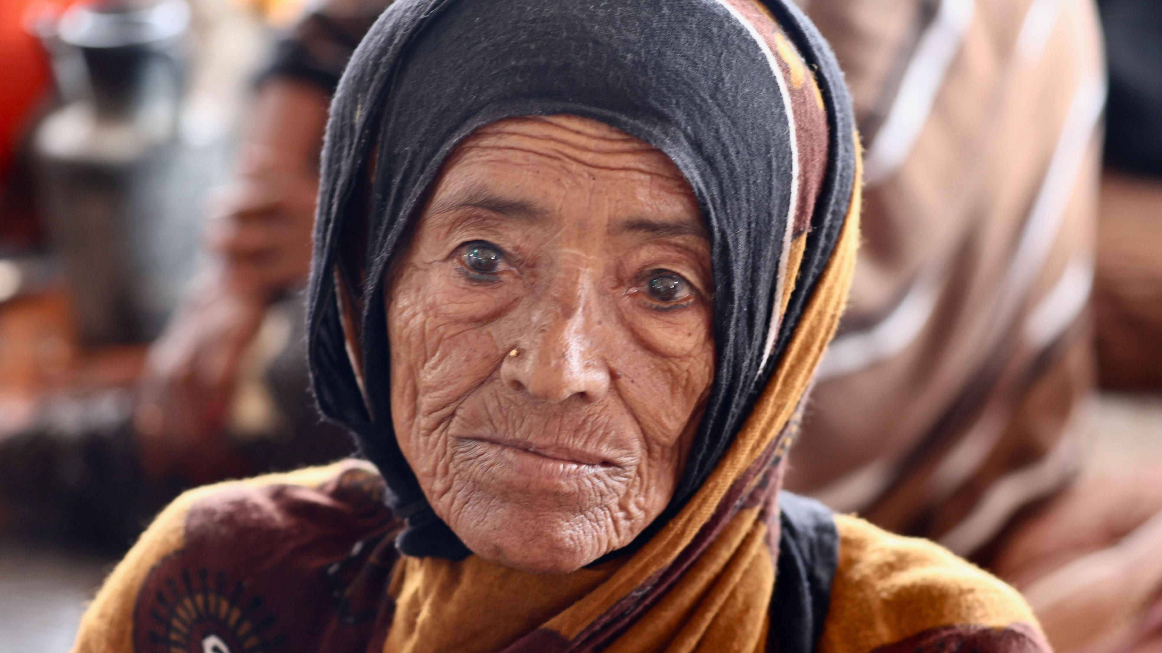 An old woman wearing black and brown garments