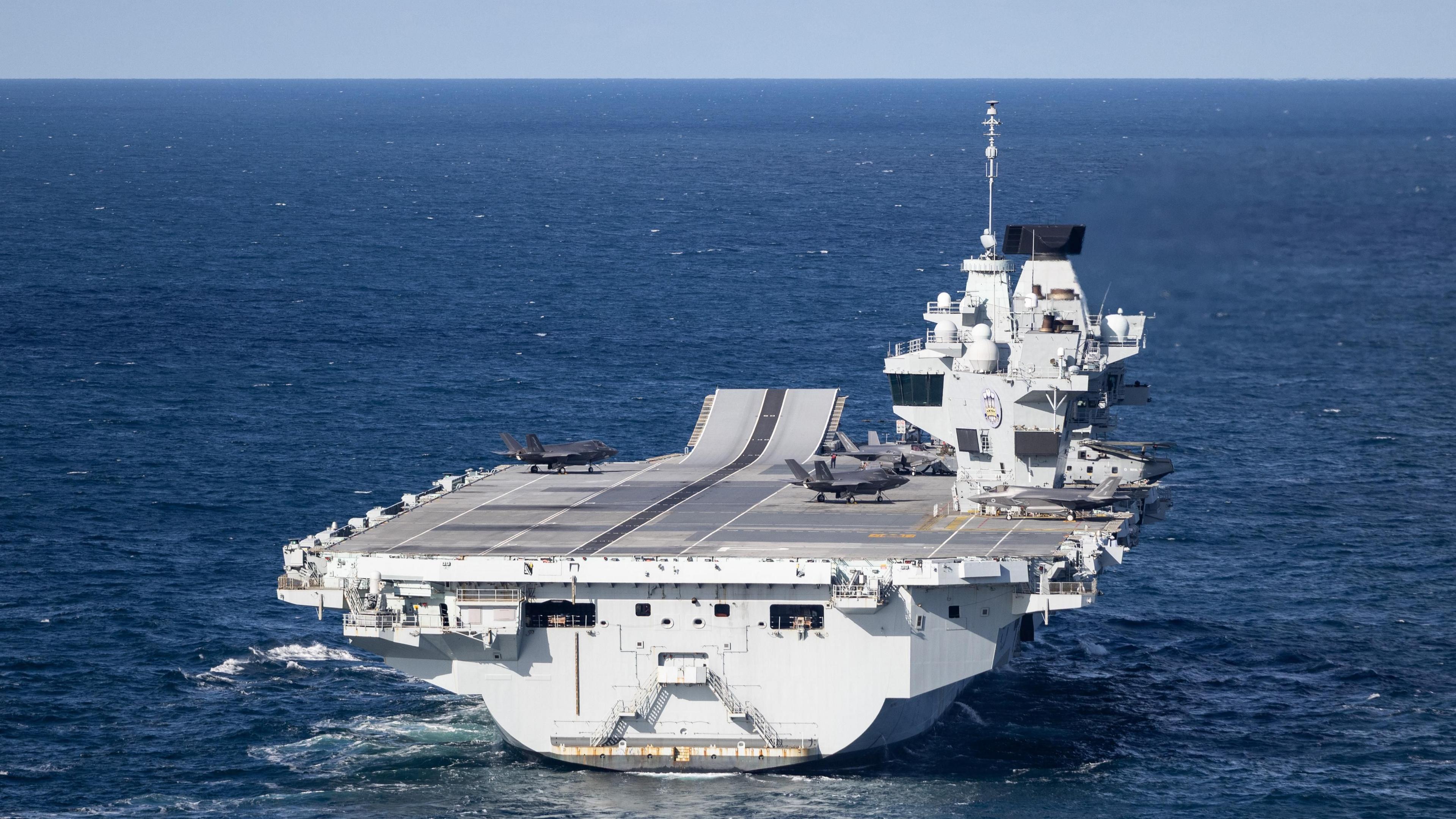 A large grey carrier is seen on the open ocean. 