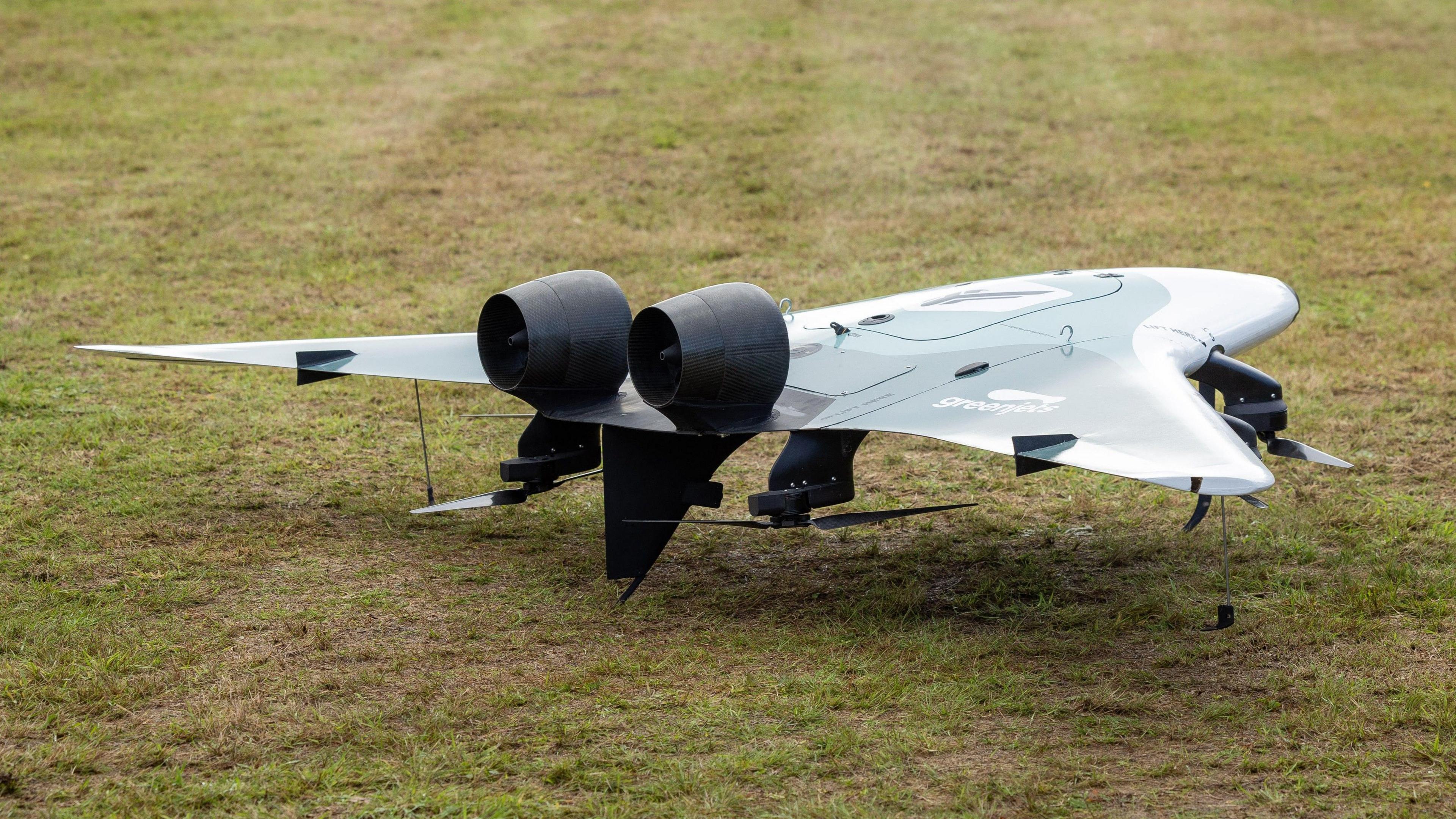 A greenjets drone has a blended wing and fuselage with two enclosed motors on the upper side. Underneath the wing are four propellers. 