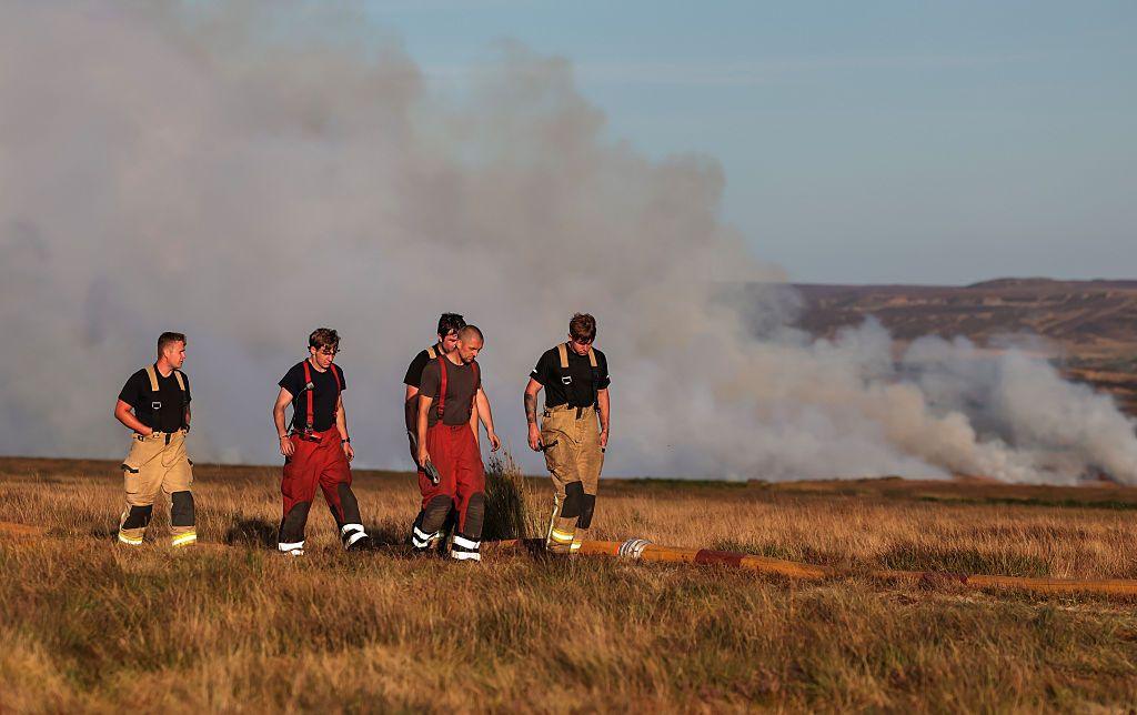 Staff walk back to base as firefighters from the Mid and West Wales and South Wales Fire Services fight wildfires on Llangynidr Moor which was declared a major incident.